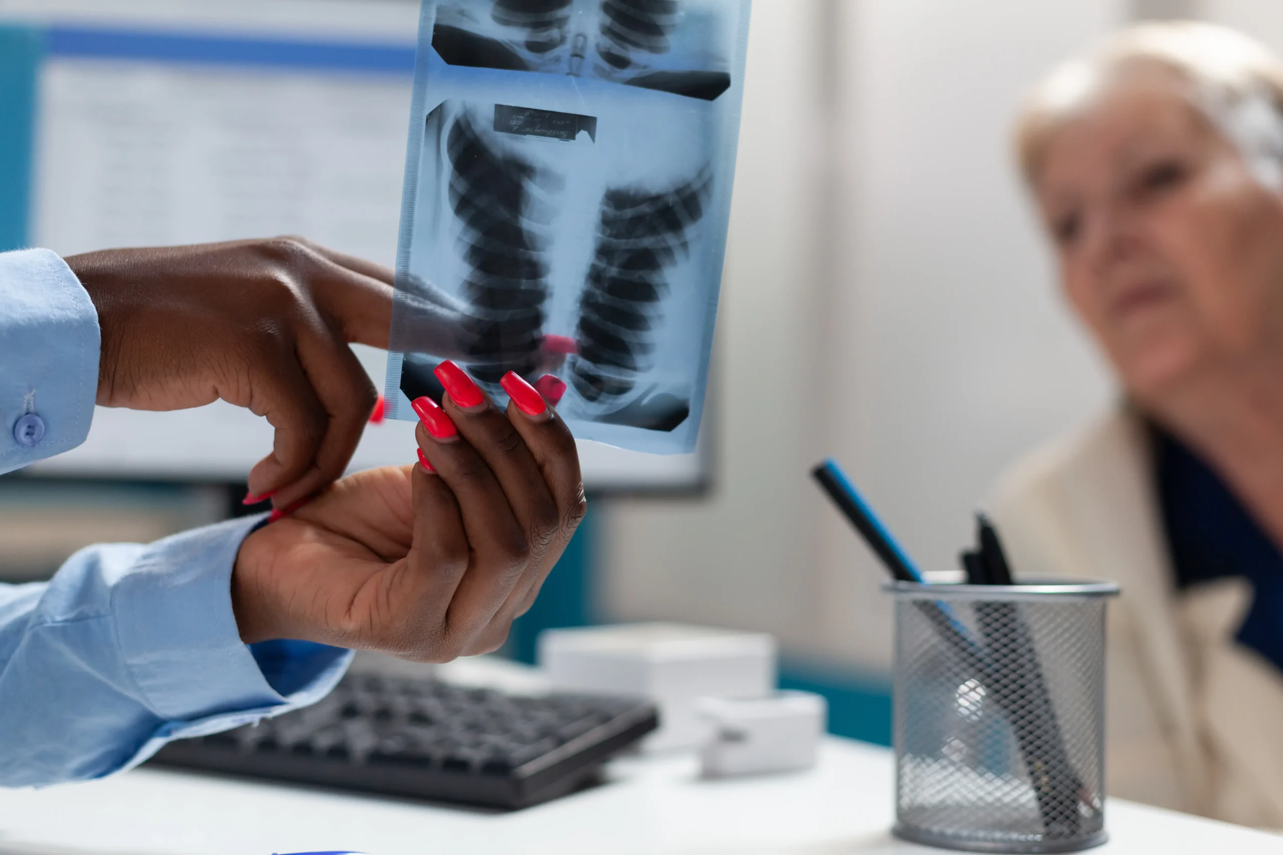 closeup therapist doctor holding lungs radiography explaining disease expertise sick senior disabled woman wheelchair medical consultation hospital office medicine concept